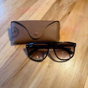 solglasögon från Ray-Ban - Snygga solglasögon från Ray-Ban med klassisk design. De har en robust båge och kommer med ett brunt fodral för säker förvaring. Perfekta för soliga dagar och ger en stilren look.