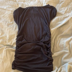 Svart t-shirt från Divided - Snygg svart t-shirt från Divided med korta ärmar och rynkade detaljer på sidorna. Perfekt för en stilren look. T-shirten är tillverkad i ett mjukt och bekvämt material.