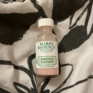 Mario Badescu Drying Lotion - En flaska med Mario Badescu Drying Lotion, perfekt för punktbehandling av finnar. Innehåller 29 ml av en rosa lotion som är känd för att effektivt torka ut blemmor över natten. En klassiker inom hudvård som många svär vid för snabb och effektiv behandling. Endast testad en gång med en bomullstops. Köparen står för frakten 💗