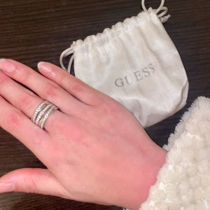 Guess Krystal Ring  - En riktigt fin Guess-ring i rostfritt stål. Ringen är robust, hållbar och i toppskick, jag har bara använt den två gånger. En dust bag medföljer vid köp. Storlek: 16 (diametern är 16 mm). Pris: 300kr, nypris kvar kring 1000 kr när jag köpte den. 