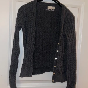 Grå stickad kofta från Odd Molly - Säljer en snygg grå stickad kofta från Odd Molly med kabelstickat mönster och knappar framtill.