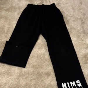 Svarta mjukisbyxor med tryck - Svarta mjukisbyxor med elastisk midja och ett coolt vitt tryck 'HIMS' vid benslutet. Perfekta för en avslappnad stil. Aldrig använt. 108 cm långa. Endast 349
