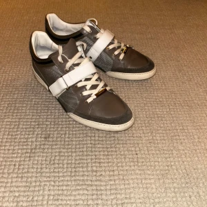 Feta sneakers från Dior  - Snygga sneakers från Dior med snörning och kardborreband. Skorna har en stilren design med en bekväm passform. Lite svart färg i fram på skosnörena men går att byta ut med extra snörena som ingår. Dustbag, kvitto och box ingår även. Nypris 9500.