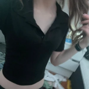 Svart croppad topp från Madlady - Säljer en svart croppad topp från Madlady. Toppen har korta ärmar och en klassisk krage med knappar framtill. Perfekt för en stilren look. Passar bra till både jeans och kjol.