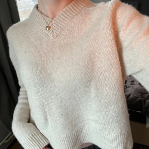 Vit stickad tröja från Tiger of Sweden - Säljer en cremevit stickad tröja från Tiger of Sweden. Tröjan har en v-ringad hals och långa ärmar med ribbade muddar. Klassisk och snygg, i 100% ull. 