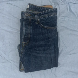 Mörkblå jeans från Jack & Jones - Snygga mörkblå jeans från Jack & Jones med klassisk femficksdesign och kontrastsömmar. Perfekta för en avslappnad stil. De har en knappgylf och en läderpatch med logga baktill.