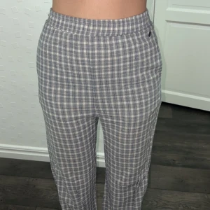 Grå rutig byxa - Snygga gråa byxor med rutig design. De har en loose passform och är högmidjade, vilket ger en bekväm och stilren look. Perfekta för en avslappnad stil.