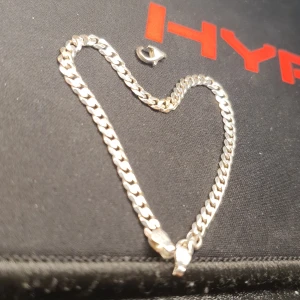 Riktig Silverarmband med kedjedesign - Snyggt silverarmband med klassisk kedjedesign. Armbandet har en robust karbinhake för säker stängning och är märkt med 925, vilket indikerar äkta silver. Perfekt för att ge en stilren touch till din outfit. En del av den är sönder och det går lätt att lösa genom en smycke butik