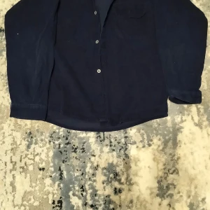 Mörkblå skjorta - Snygg mörkblå skjorta med långa ärmar och knappar framtill. Perfekt för en stilren look. Skjortan har en klassisk design som passar till många tillfällen.