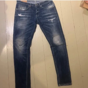 Dondup George jeans - Snygga blå jeans med slitningar på knäna och låren. De har en klassisk femficksdesign och en dragkedja framtill. Perfekta för en avslappnad stil.