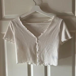 Vit ribbad kortärmad topp -  vit ribbad topp med korta ärmar och knappar framtill. Den är i storlek M men skulle säga att den är mindre i storleken så den passar S. Har inte använt då den varit för liten 