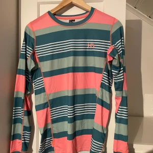 Randig långärmad tröja från Kari Traa - Säljer en färgglad långärmad tröja från Kari Traa i randigt mönster med rosa, gröna och blå nyanser. Perfekt för en sportig look med sin bekväma passform och stilrena design. Bra till lager på lager klädsel