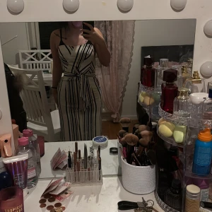 Randig two peace  med bälte - Snygg randig  svart och vit med ett matchande bälte i midjan. Klänningen har smala axelband och en figurnära passform som framhäver silhuetten. Perfekt för en stilren look.