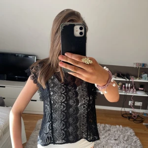 Svart spetsblus - Säljer en svart spetsblus med korta ärmar och vackra detaljer (visar med ett linne under). Blusen har en rund hals och en dragkedja i ryggen. Väldigt fin och nästan aldrig använd🩷