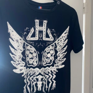Svart t-shirt med vit tryck - Snygg svart t-shirt från Horspist med ett iögonfallande vitt tryck. Kortärmad och tillverkad i mjukt material för bekväm passform. Storlek L men sitter som medium