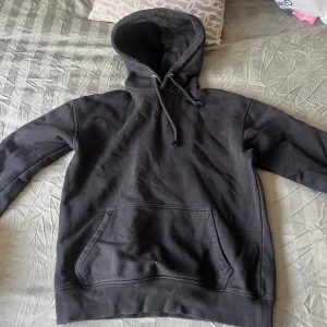 Svart hoodie - Säljer en klassisk svart hoodie med justerbar huva. Perfekt för en avslappnad stil och passar till det mesta. Skön och enkel att bära.