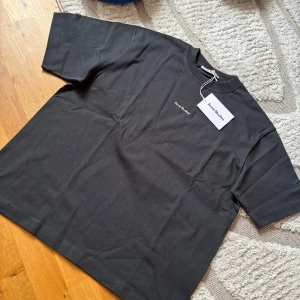 Svart t-shirt från Acne Studios - Helt ny svart t-shirt från Acne Studios i 100% bomull. Den har en klassisk passform med korta ärmar och en rund halsringning. Perfekt för en stilren look.
