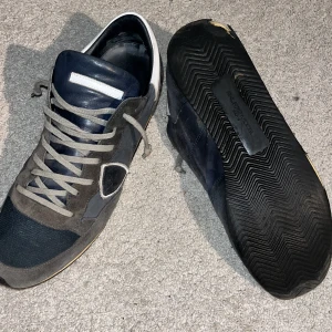 Grå och blå sneakers från Philippe Model - Snygga sneakers från Philippe Model i grått och blått med vita detaljer🔵⚪️. Skorna har en stilren design med snörning och en robust sula. Perfekta för en casual look😌. Säljer av för jag hade dem till vintern men nu försöker jag spara ihop till ett par valentinos. Skriv vid minsta fundering 💭. kom med prisförslag finns inga skambud!!