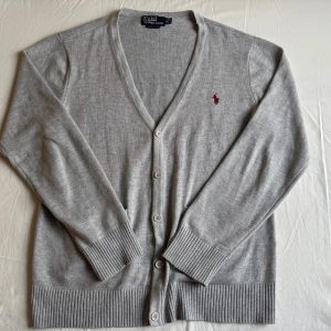 Grå kofta från Ralph Lauren - Säljer en stilren grå kofta från Ralph Lauren i 100% bomull. Extremt bra skick inga fläckar eller defekter. Storleken är L. Sitter bra på modellen som är 184 cm. Skriv vid funderingar!