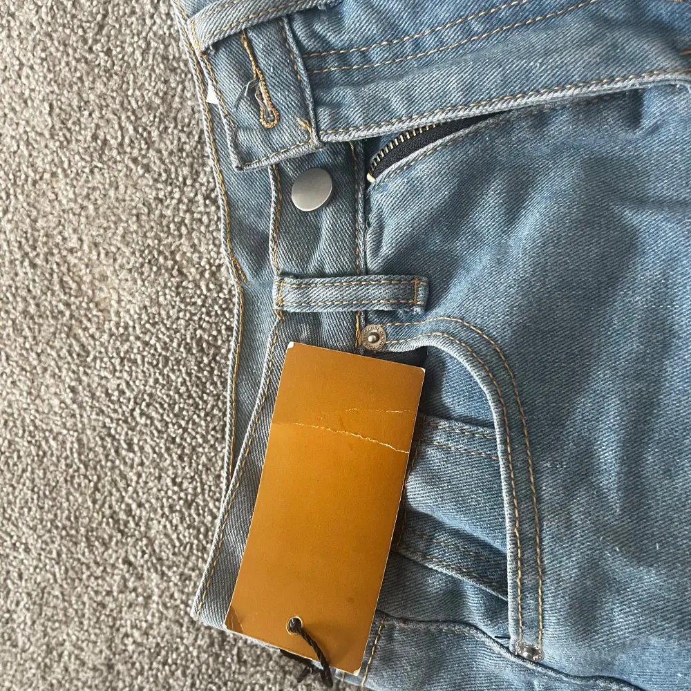 Snygga blå jeans med slitningar på knäna och fransiga kanter. De har en bootcut-stil som ger en avslappnad look. Perfekta för en trendig vardagsstil. Mått: innerbenslängd ~72cm midjemått ~33x2 cm. Farkut & Housut.