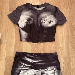 Svart och vit kjol med tryck - Snygg kortkjol i svart och vitt med ett unikt tryck. Kjolen har en modern design med veckdetaljer framtill. Perfekt för dig som vill sticka ut med en cool look.