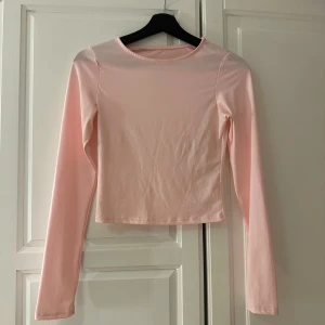 Ljusrosa långärmad topp - Säljer en stilren ljusrosa långärmad topp. Perfekt för en enkel och elegant look. Toppen har en rund hals och är i ett mjukt material som känns skönt mot huden.  🌸
