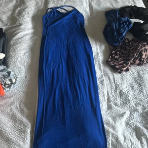 Blå långklänning - Elegant blå långklänning med smala axelband och en stilren design. Perfekt för speciella tillfällen där du vill sticka ut. Klänningen har en smickrande passform och är tillverkad i ett mjukt material som faller fint.