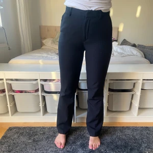 Svarta kostymbyxor - Säljer ett par stilrena svarta kostymbyxor. De är högmidjade och har en straight passform som ger en klassisk look. Perfekta för både kontoret och mer formella tillfällen.