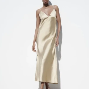 Zara Satinklänning  - Superfin långklänning från Zara i champagne färg! Använd ca 3 gånger men så i allmänt fint skick, däremot finns de några små repor på klänningen som man inte lögger märke till, samt ett litet hål vid under armen som inte heller märks särskilt mycket!