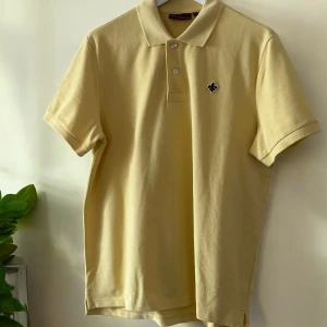 Gul pikétröja med broderad detalj - Gul Morris pikétröja, helt oanvänd. Storlek S men i mitt tycke något ”oversized”. 