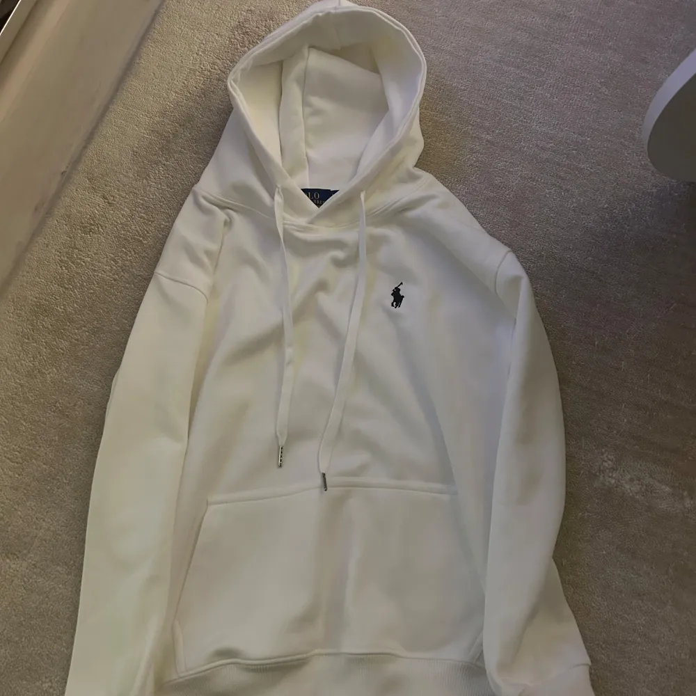 Säljer en stilren vit hoodie från Ralph Lauren med den klassiska loggan på bröstet. Den är i mycket bra skick och perfekt för både höst och vår. (St: M passar S).Hoodien har en känguruficka och justerbar huva med snören. Superbekväm och passar till allt! 🕶️. Tröjor & Koftor.