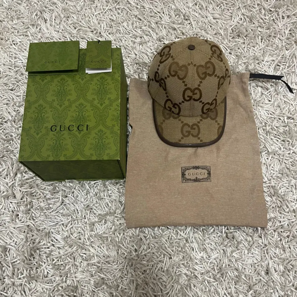 Säljer en snygg Gucci keps i beige med det klassiska GG-mönstret. Kepsen är i mycket bra skick och kommer med originalförpackning och dustbag. Perfekt accessoar för att lyfta vilken outfit som helst. Justerbar passform för att sitta perfekt på huvudet.. Accessoarer.