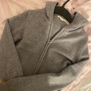 Grå stickad hoodie från gina - Säljer en supermysig grå stickad hoodie med dragkedja. Den är croppad och har långa ärmar med ribbade muddar. Den är perfekt för höst och vinter. Den passar bra till både chill och casual outfits. Har använt endast en gång och säljer för att jag hade en annan i rosa jag tyckte om mer. Köpt för 250 inne på Gina och säljer för 200. Skriv till mig om det finns fler frågor💘