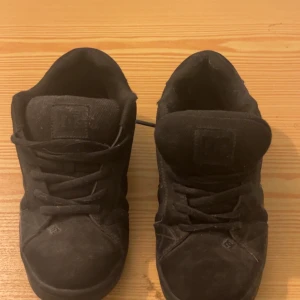 Svarta sneakers från DC - Säljer ett par svarta sneakers från DC i bra skick. Skorna är i mocka och har en klassisk design med snörning. Perfekta för vardagsbruk och ger en cool stil. Storlek 40, passar bra för höst och vår. OBS! SKORNA BLIR TVÄTTADE INNAN FRAKT!!