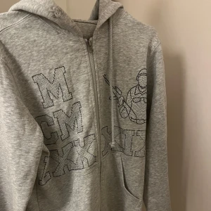 Grå hoodie med tryck - Säljer en grå hoodie med fint tryck på framsidan. Den har en dragkedja och en skön huva, perfekt för vardagsbruk. Köpt från ett UF företag för nått år sen🤍 passar xs-s