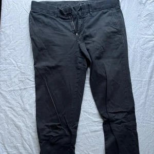 Svarta byxor från J.Lindeberg - Säljer ett par stilrena svarta byxor från J.Lindeberg i bra skick. De har en klassisk design med knappar och dragkedja framtill. Perfekta för både vardag och fest. Passar bra till höst och vår.