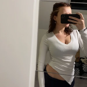 Vit långärmad topp - Säljer en snygg vit långärmad topp i ribbat material. Den har en v-ringad design som ger en stilren look. Perfekt för både vardag och fest! Passar bra till jeans eller kjol. Hör av dig vid intresse!, storlek xs men väldigt stretchiga så passar både S och M 