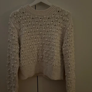Beige stickad tröja - Mysig vit/beige stickad tröja med ett vackert mönster. Perfekt för kyliga dagar med sin varma och bekväma design. Tröjan har långa ärmar och ribbade kanter vid hals, ärmslut och nederkant. 