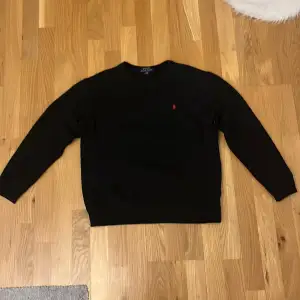 Säljer en stilren svart tröja från Polo Ralph Lauren i storlek S. Den har en klassisk design med långärmade ärmar och en liten röd logga på bröstet. Perfekt för både vardag och festliga tillfällen. Tröjan är i mycket bra skick och redo för en ny ägare!