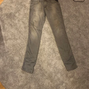 Grå jeans från Replay - Säljer ett par grå jeans från Replay i bra skick. De har en snygg, lite sliten look och är i en slim passform. Perfekta för både vardag och fest! De är är väldigt laidback och avicci grisch. Ny pris 1200 mitt pris 400kr. Waist 30 längd 34. Skriv vid minsta lila fråga. 