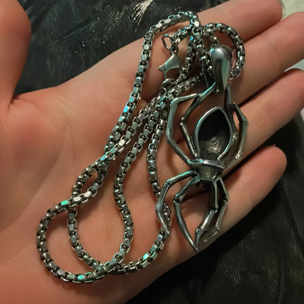 Coolt och edgy halsband i silverfärg med en unik hängande spindel och dödskalle-design. Perfekt för att ge din outfit en tuff touch. Kedjan är robust och hängsmycket är detaljerat med en skrämmande look. Passar perfekt för halloween eller som ett statement-smycke.. Accessoarer.