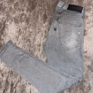 Gråa Replay jeans - Säljer ett par snygga grå jeans från Replay. På baksidan av jeans finns det en lite svart prick och en större. De har en klassisk femficksdesign och en stilren look. Perfekta för både vardag och fest! 🕺