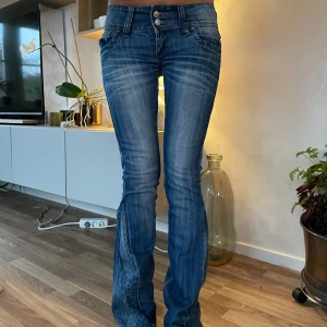 Lågmidjade jeans - Ett par snygga blå bootcut jeans i bra skick. De har coola leoparddetalerj på utsidan av benen och är lågmidjade med dubbla knappar fram. 🐆💙Alla mått finns på bild 5. Skriv för frågor