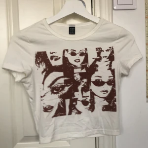 Vit t-shirt med tryck från SHEIN - Säljer en vit t-shirt från SHEIN i storlek XS. Den har ett unikt tryck med ansikten i brunt på framsidan. Perfekt för en avslappnad stil eller en dag ute med vänner. T-shirten är kortärmad och i bomullsmaterial. Skicka ett meddelande vid intresse!