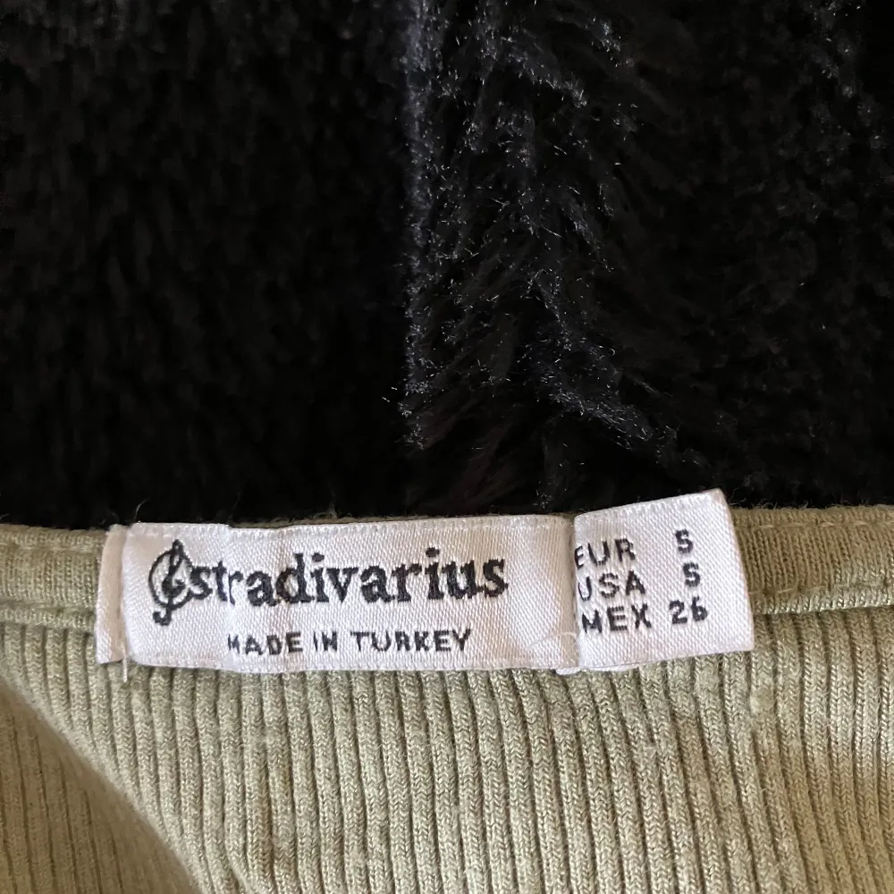 Säljer en grön ribbad topp från Stradivarius. Den har en v-ringad design och spetsdetaljer på ärmarna. Köpt i Frankrike. Yläosat.