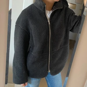 Svart/grå teddyjacka med dragkedja - Mörkgrå teddyjacka/pile-jacka. Inte använd  mycket. Storlek xs, men oversized och gosig. Spegeln är lite skitig, så jackan är ren! Jackan går inte att köpa på hm längre! 