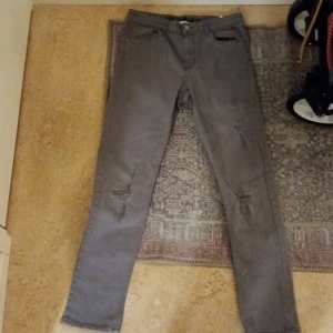 Grå skinny jeans - Snygga grå skinny jeans med slitna detaljer på knäna. Perfekta för en trendig look. De har en klassisk femficksdesign och knappgylf. Pris kan diskuteras .
