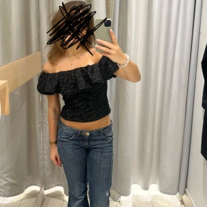 Svart glittrig offshoulder topp - Snygg svart glittrig offshoulder topp med volangdetaljer. Perfekt till nyår💕