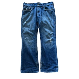 True Religion Billy - True Religion Billy i okej skick. Storlek W33 flared passform, lite wear förekommer på kanten till fickorna och lite hål och slitningar på hälen som man inte lägger någon märke till. Allt annat är i bra skick.