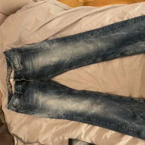 Blå jeans - Säljer ett par blå jeans med snygga slitningar och en klassisk femficksdesign. De har en normal straight leg baggy stil och är low/midwaist alldrig använt endast testat. märket heter denim by soccx. storlek midja-32 längd-32